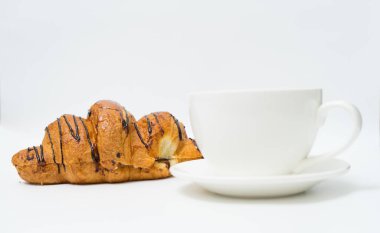Üst ya da düz kahve fincanı ve kruvasanla beyaz arka planda fotokopi alanı. Sabah kahvesi ve atıştırmalık.