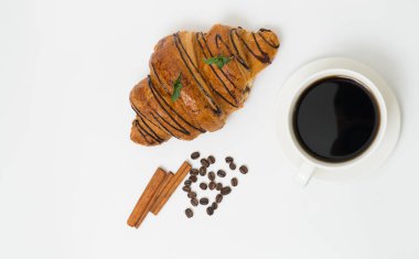 Üst ya da düz kahve fincanı ve kruvasanla beyaz arka planda fotokopi alanı. Sabah kahvesi ve atıştırmalık.
