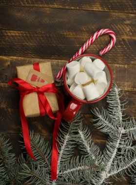 Marşmelovlu bir fincan kahve ve ahşap arka planda bir pipet. Noel