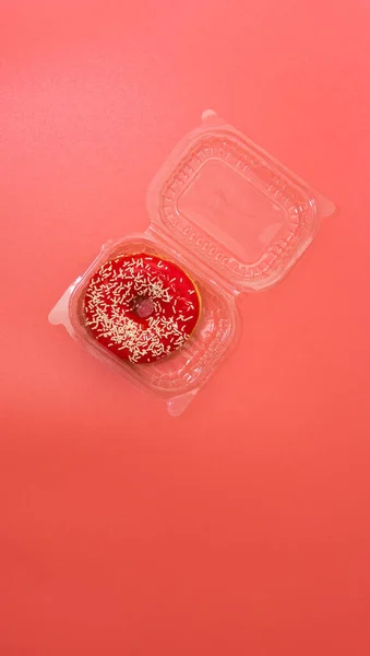 Pembe kremalı çörek ve pembe arka planda bir gökkuşağı plastik bir botta, paket çörek. Paket yemek. Parlak pembe arkaplan