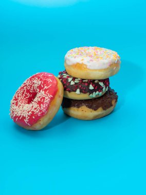 Mavi arkaplanlı renkli yuvarlak çörekler. Tatlı. Düz yatış, üst manzara..