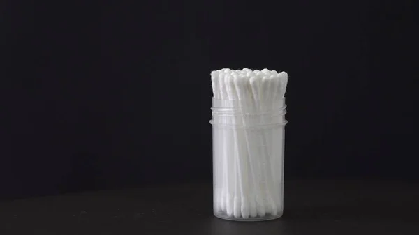 White cotton swabs. Rotation of the object. Black background. Hygiene products. White plastic. Medical topics. Cleansing. A smear for analysis. Demonstration of the product. Close-up.