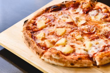 Lezzetli bir Hawaii geleneği ve salamlı pizza pişirme malzemeleri siyah masa üzerinde domuz pastırması domatesleri orijinal restoran arka planında. Acı biberli pizzanın en iyi manzarası. Uzayı kopyala Odun ateşli fırın pizzası.