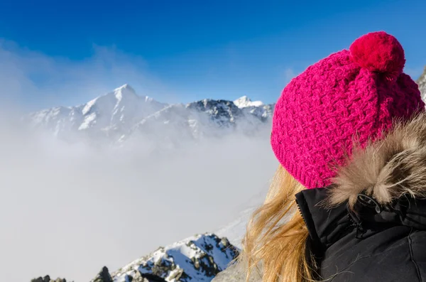 Mulher com chapéu colorido com vista para as montanhas de inverno — Fotografia de Stock