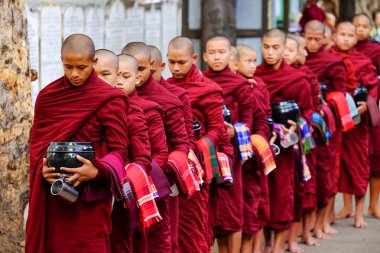 AMARAPURA, MYANMAR - JUNE 28, 2015: Buddhist monks queue for lun clipart