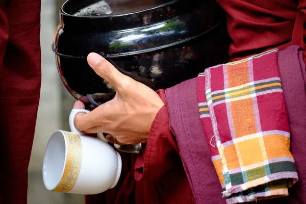 Detalles coloridos de manos de monje budista sosteniendo un tazón y una taza — Foto de Stock