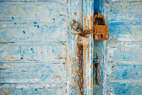 Старый ржавый замок и цепь на выветренной текстурированной двери — стоковое фото