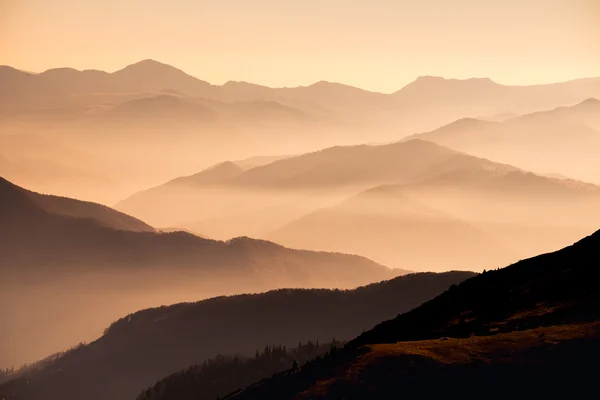 Vista paisagem de montanhas nebulosas ao pôr-do-sol — Fotografia de Stock