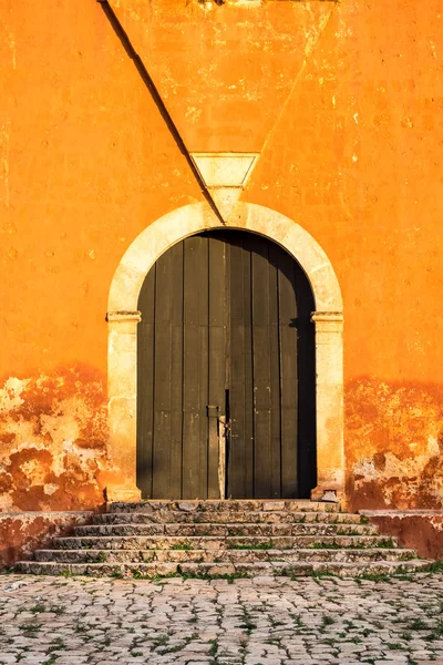 Detail dřevěné dveře v jasně oranžové zdi s texturou — Stock fotografie