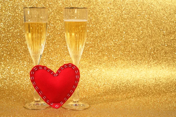 Zwei Gläser Champagner und rotes Herz mit goldenem Glitzerlicht auf Hintergrund — Stockfoto