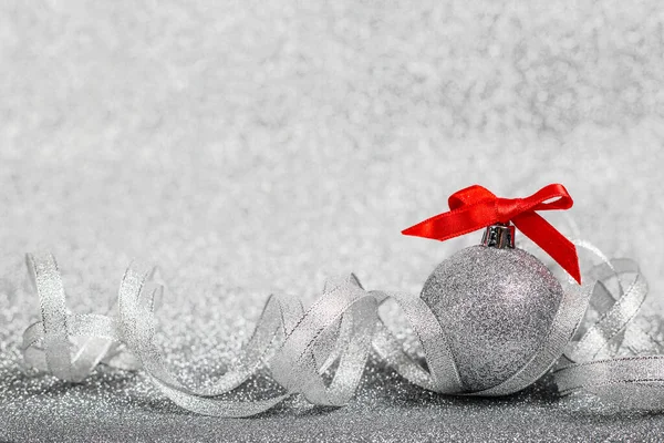 クリスマスの休日組成のお祝いの装飾ボールとともに赤いリボン弓上のシルバーグリッターボケ背景 — ストック写真
