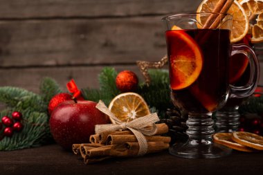 Tarçınlı sıcak şarap portakal köknar ağacı dalına yapışır ve koyu ahşap arka planda noel kompozisyonu takılır.