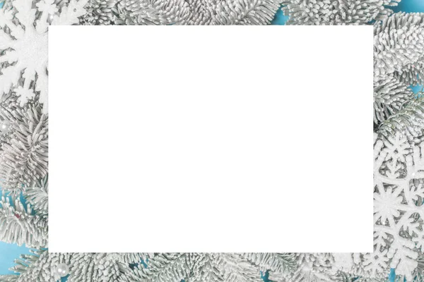白い長方形のカードと青の背景に霜モミの木の小枝とクリスマスの装飾的な雪の結晶テキストテンプレートフラットレイトップビューデザインのためのコピースペース — ストック写真