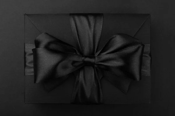 黒い金曜日の贈り物 テキストのためのコピースペースを持つ黒い紙の背景にシルクリボン弓付きの紙箱 フラットレイトップビューテンプレート — ストック写真