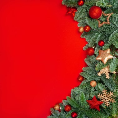 Kırmızı arkaplanda Noel ağacı dalları ve süslemeler için süsleme çerçevesi ve metin için kopyalama alanı