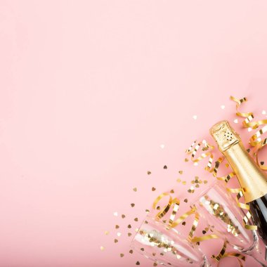 Sevgililer günü şampanya şişesi flüt bardakları altın konfeti kalpleri ve pembe arka planda yılan yağı metin için yer var.