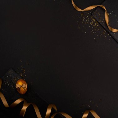 Altın lüks paskalya yumurtaları ve kurdele kompozisyon çerçevesi siyah taş zemin üzerinde metin kartı için fotokopi alanı ile