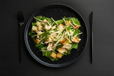 Sezar salatası kalp şeklinde aşk yemeği konsepti, siyah taş lüks tabak, düz görünüş tasarımı, siyah arka plan