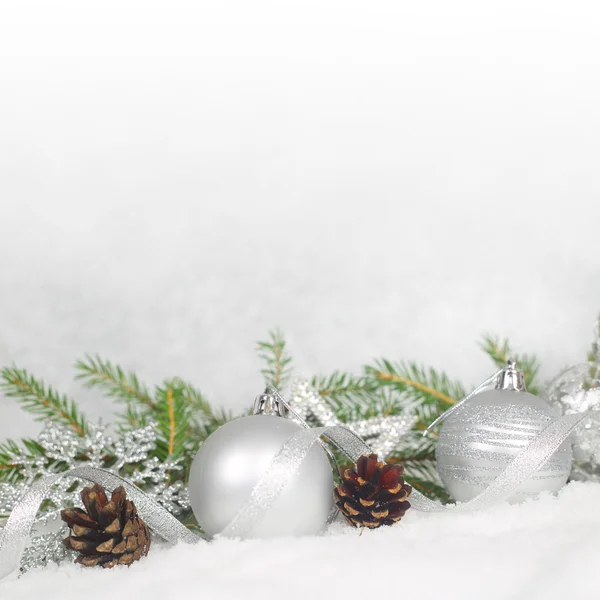 Julgranskulor, kottar och grön gran gren på snö — Stockfoto