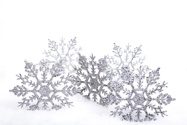 Copos de nieve decorativos de plata en la nieve, espacio de copia blanca — Foto de Stock