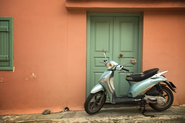 Scooter azul em uma parede de pêssego — Fotografia de Stock