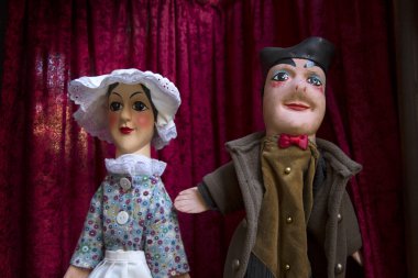 Man and woman guignols on a red curtains