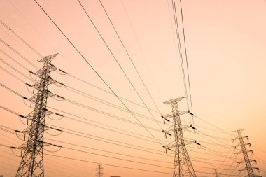 Gökyüzü günbatımı arka planında yüksek voltaj direği.