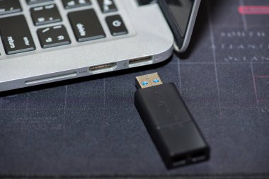 Yakın plan resim bir dizüstü bilgisayara bağlanmak için USB flaş bellek kullanımını gösterir. Elle taşınan bellek belleği bir bilgisayar portuna takılıyor.