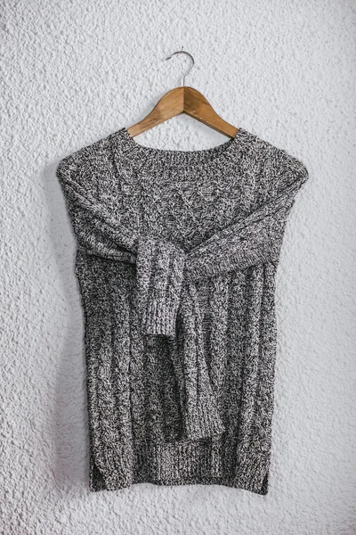 Pullover hanging on wood hanger on wall background. — Stock Photo, Image