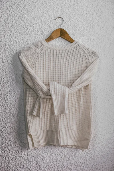 Pullover hängt auf Holzbügel an der Wand Hintergrund. — Stockfoto