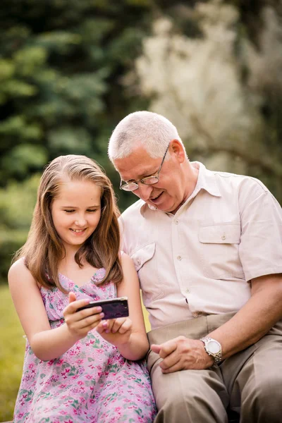 Grandchild shows grandfather smartphone — Stock Photo, Image