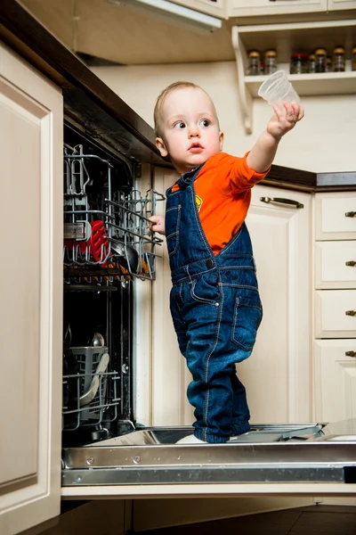 Младенец помогает разгрузить посудомоечную машину — стоковое фото