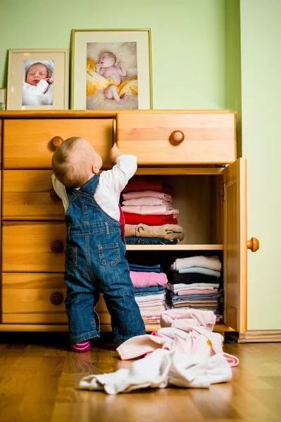 Domestic chores - baby throws out clothes — Stock Photo, Image