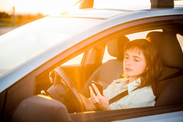 Driving car and looking in phone — Stock Photo, Image