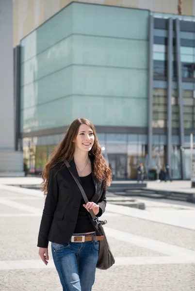 Mujer joven con el bolso del ordenador portátil caminando calle — Foto de Stock