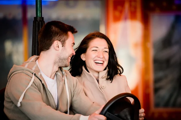 Pareja joven montando coche en el parque de atracciones — Foto de Stock