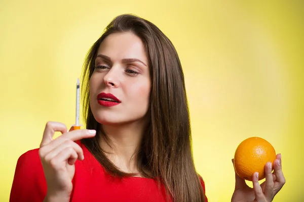 Жінка тримає шприц і апельсин — стокове фото