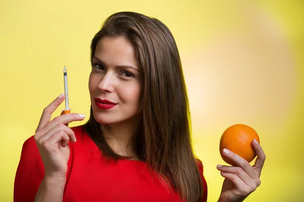 Donna con in mano una siringa e un'arancia — Foto Stock
