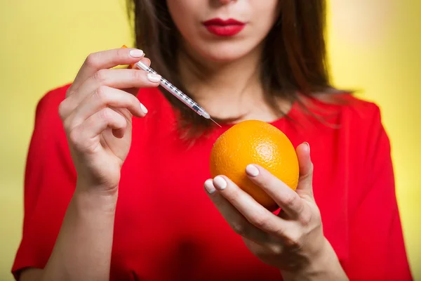 Mulher segurando uma seringa e uma laranja — Fotografia de Stock