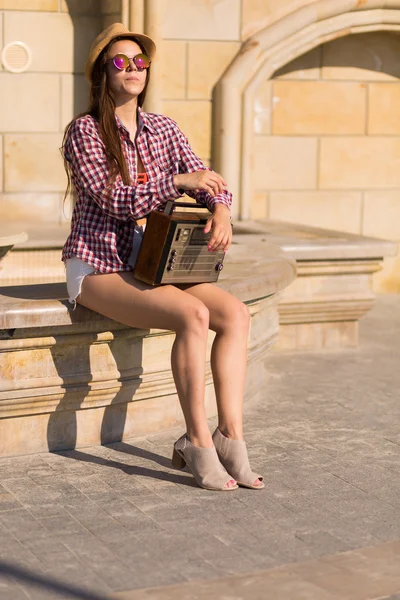 Schöne junge Boho-Frau mit einer Retro-Stereoanlage, die auf einer Saite sitzt — Stockfoto