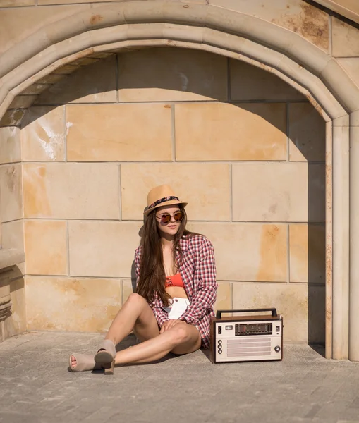 Schöne junge Boho-Frau mit einer Retro-Stereoanlage, die auf einer Saite sitzt — Stockfoto