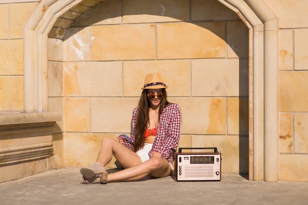 Schöne junge Boho-Frau mit einer Retro-Stereoanlage, die auf einer Saite sitzt — Stockfoto