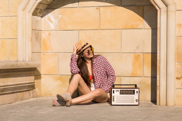 Mooie jonge boho vrouw met een retro stereo zittend op een stre — Stockfoto