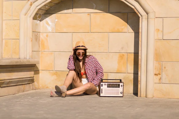 Beautiful young boho woman with a retro stereo sitting on a stre — Stock Photo, Image