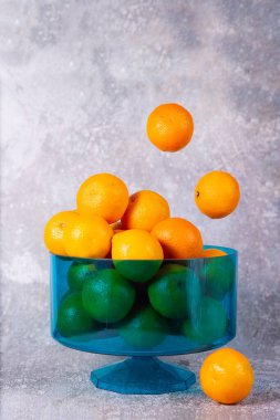 Mandalinalar gri arka planda mavi kasede.