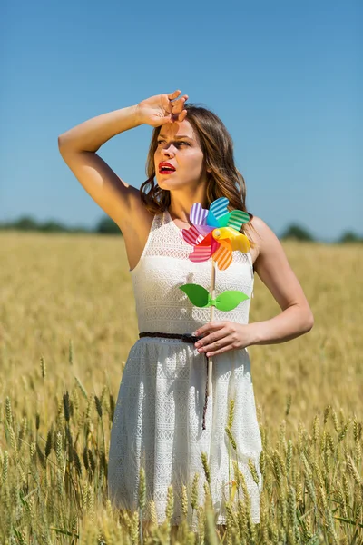 Glad pige med en farverig vindmølle - Stock-foto
