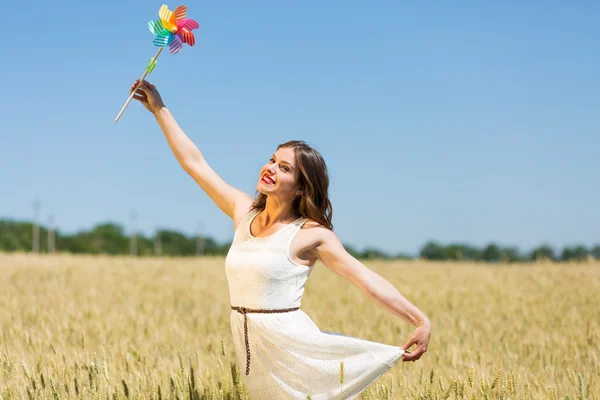 Счастливая девушка с красочной ветряной мельницей — стоковое фото