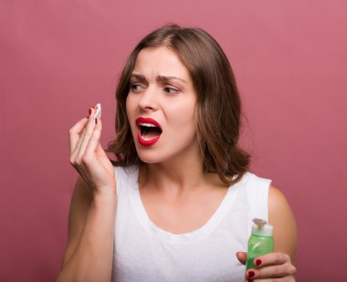 Bir losyon ve bir pamuk yastık tutan kadın