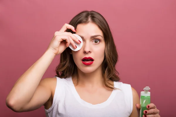 Mujer sosteniendo una loción y una compresa de algodón — Foto de Stock