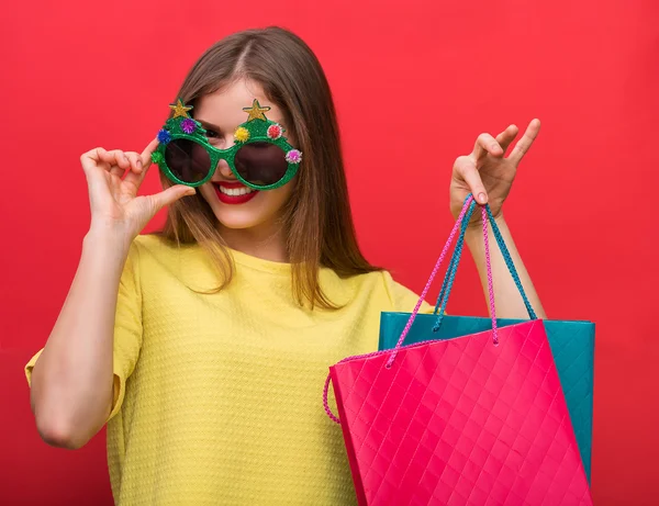 Žena s vánoční večírek brýle a nákupní tašky — Stock fotografie
